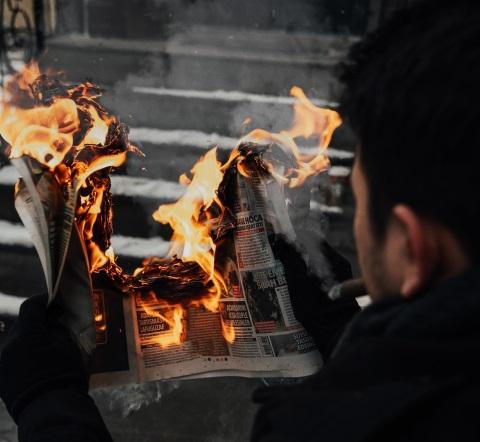 Foto eine Person hält eine brennende Zeitung